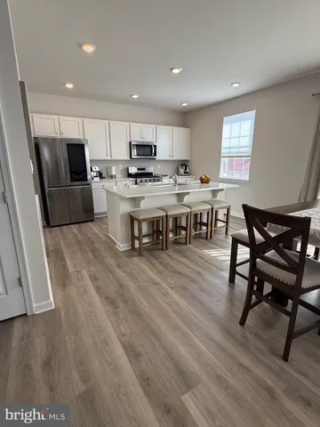 a kitchen with stainless steel appliances kitchen island granite countertop a table chairs sink and cabinets