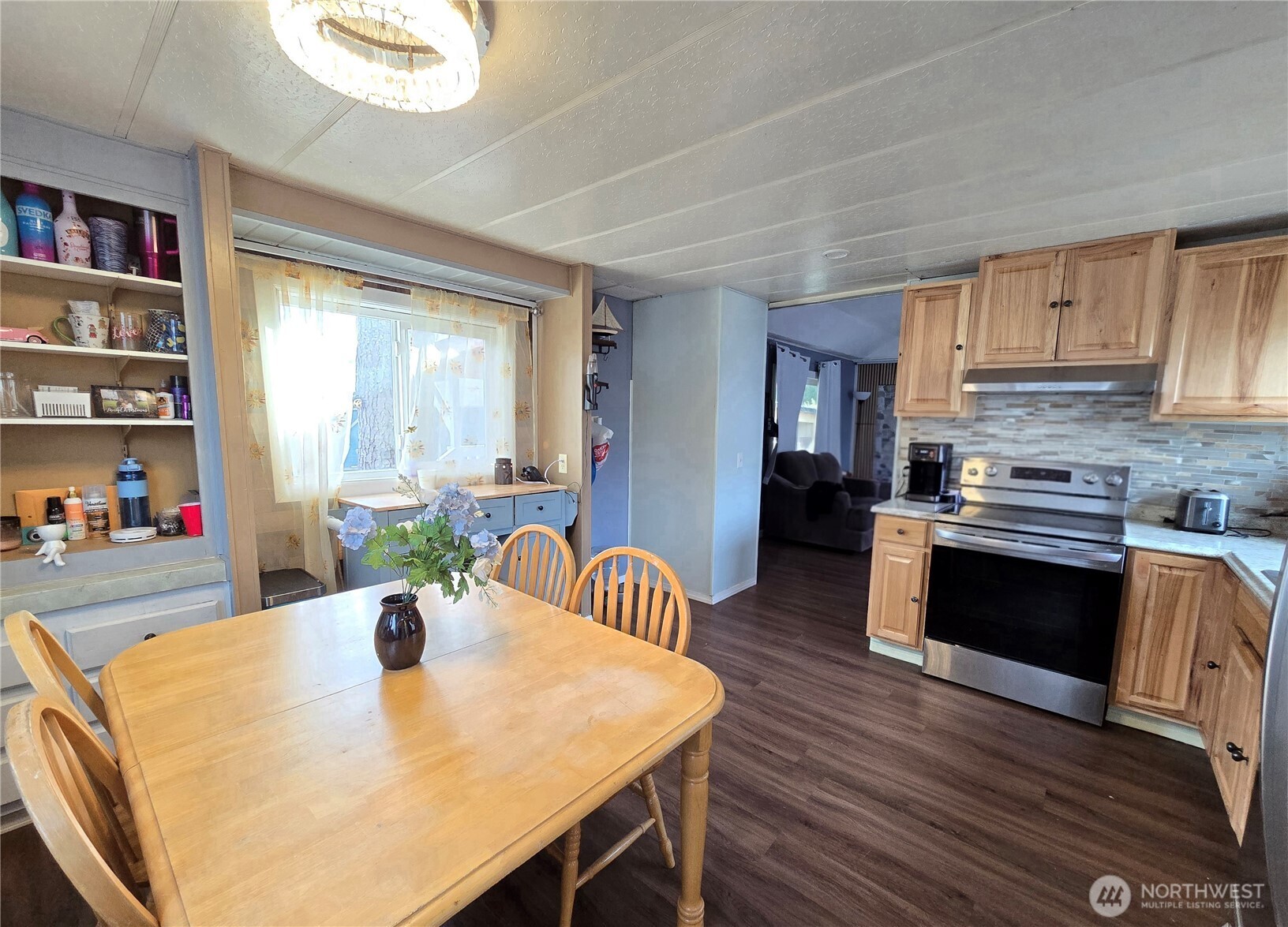 38 Hurd Road, Unit 35 Elma, WA 98541 - Photo 5 of 20 a kitchen with stainless steel appliances granite countertop a stove a refrigerator a sink a dining table and chairs with wooden floor