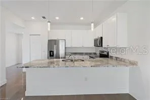 a kitchen with kitchen island granite countertop a sink stove and refrigerator