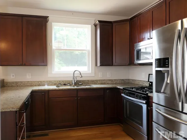a kitchen with granite countertop a sink stove and refrigerator