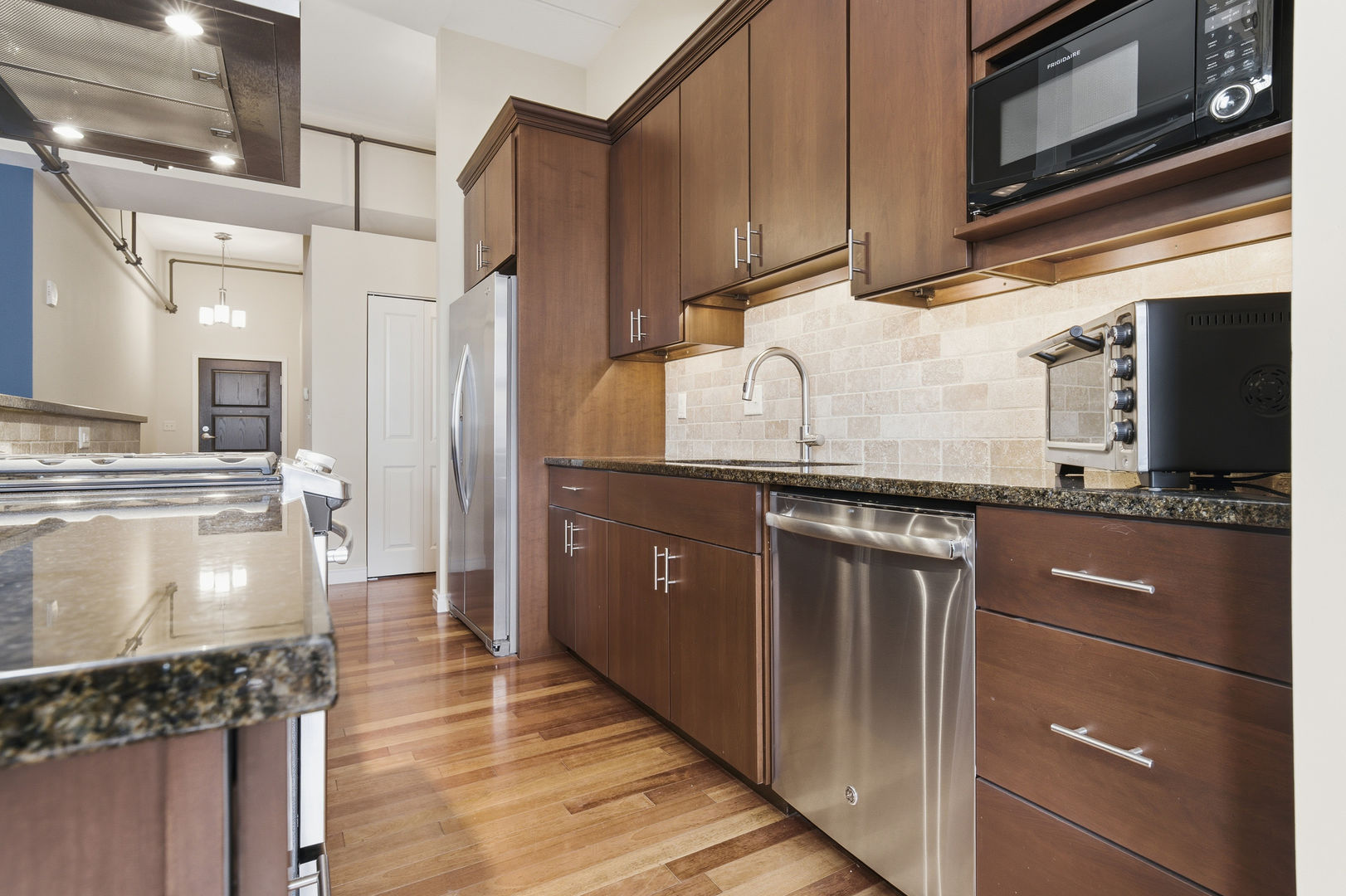 212 North Center Street, Unit 301 Bloomington, IL 61701 - Photo 9 of 39 a kitchen with kitchen island granite countertop stainless steel appliances and wooden cabinets