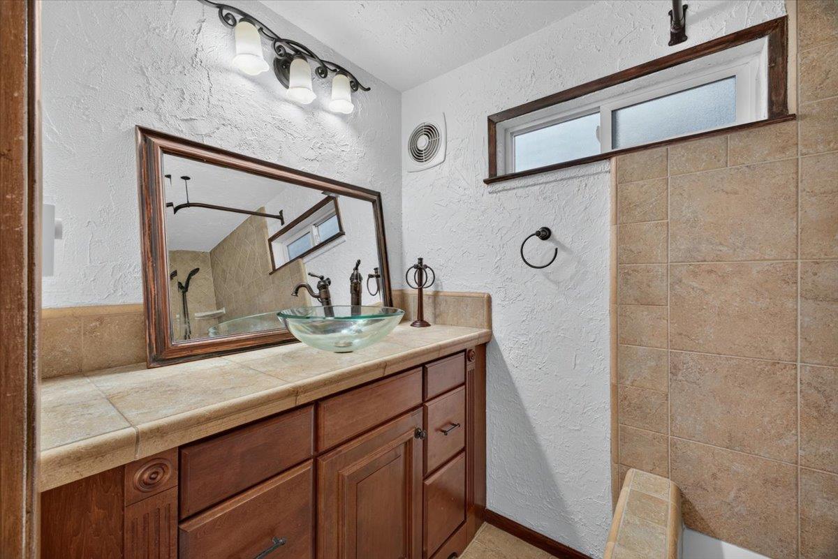 514 Primavera Road Boulder Creek, CA 95006 - Photo 5 of 40 a bathroom with a granite countertop sink a mirror and shower