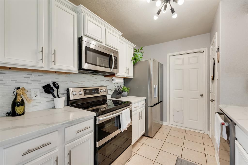 149 Cattlemans Creek Road Newark, TX 76071 - Photo 8 of 39 Kitchen has quartz countertops, tile backsplash, pantry and door to 2-car garage at 149 Cattlemans Creek Rd in the Chisholm Springs neighborhood in Newark, TX 76071