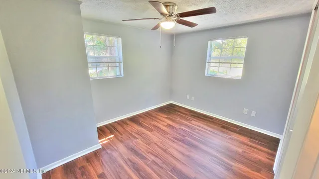 an empty room with wooden floor closet and windows