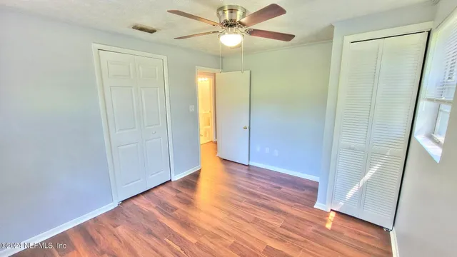 a view of empty room with wooden floor and fan