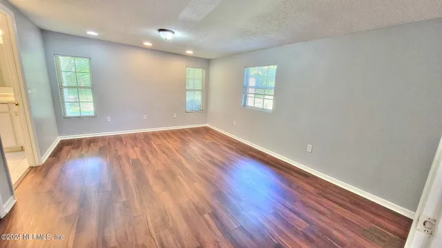 an empty room with wooden floor and windows