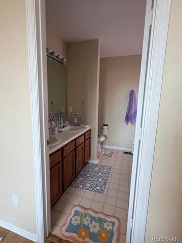 a spacious bathroom with a double vanity sink a mirror and a toilet