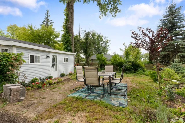 a view of backyard with table and chairs and a large tree