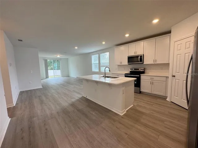 a kitchen with stainless steel appliances a refrigerator a stove top oven and a sink