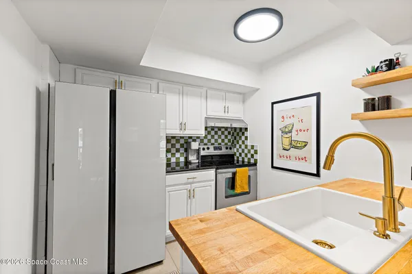 a kitchen with stainless steel appliances granite countertop a refrigerator a stove and a sink with wooden floor