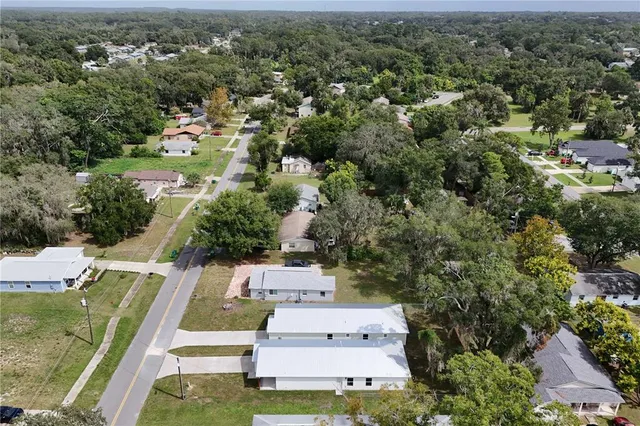 an aerial view of residential houses with outdoor space and trees