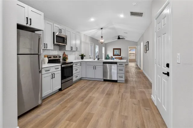 a kitchen with stainless steel appliances a stove top oven a refrigerator a sink and dishwasher
