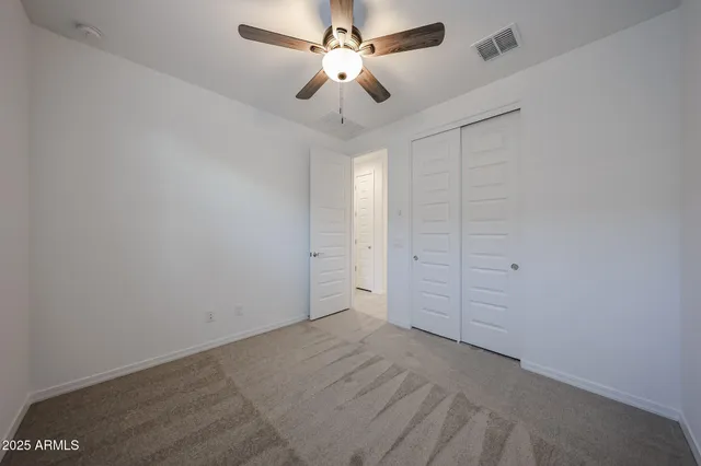 en empty room with closet and ceiling fan