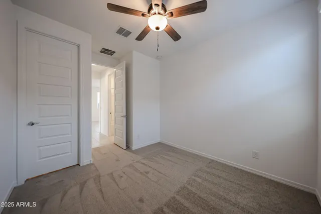 an empty room with closet and a chandelier fan