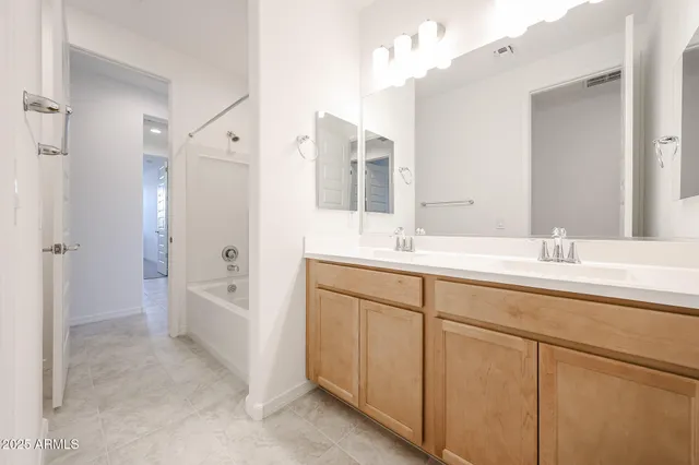 a bathroom with a sink double vanity granite tub shower and a mirror