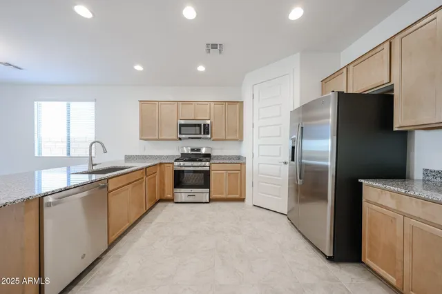 a large kitchen with cabinets stainless steel appliances and a window