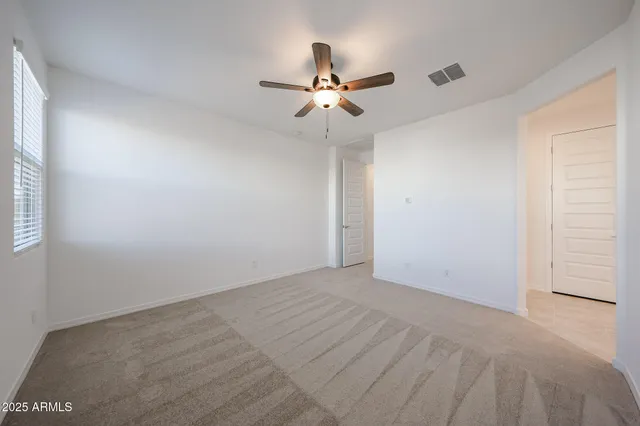 an empty room with a ceiling fan and wooden floor