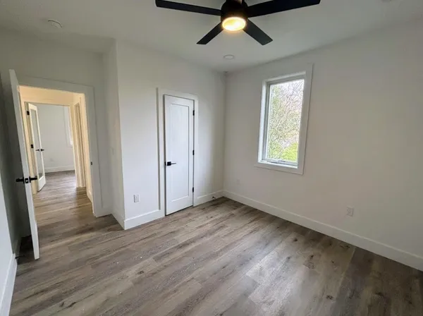 an empty room with wooden floor cabinet and windows