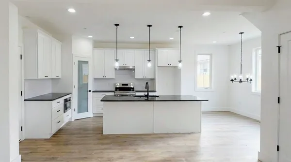 a kitchen with stainless steel appliances granite countertop a sink a stove and a refrigerator