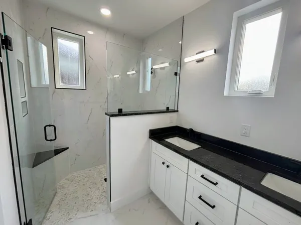a bathroom with a granite countertop sink a toilet a mirror and shower