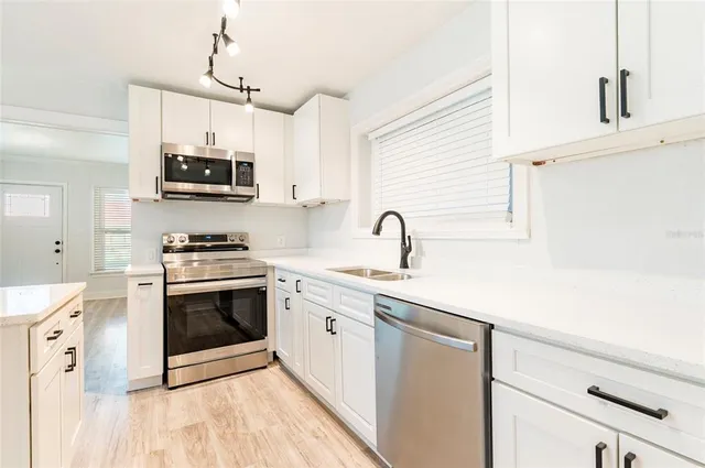 a view of a kitchen with wooden floor and stainless steel appliances