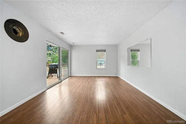 an empty room with wooden floor and windows