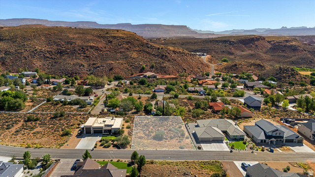 Level lot situated between established residences, featuring a paved road frontage and surrounded by natural desert landscaping