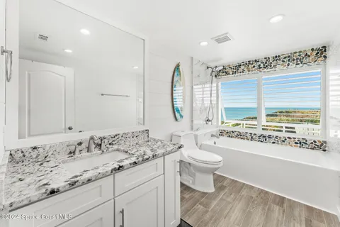 a bathroom with a granite countertop sink toilet and large mirror