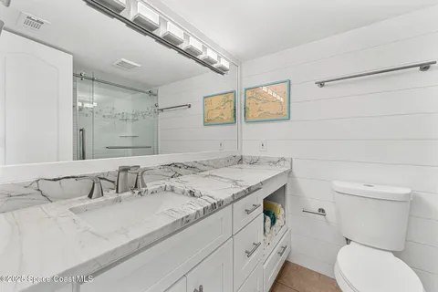 a bathroom with a granite countertop sink a toilet and a mirror