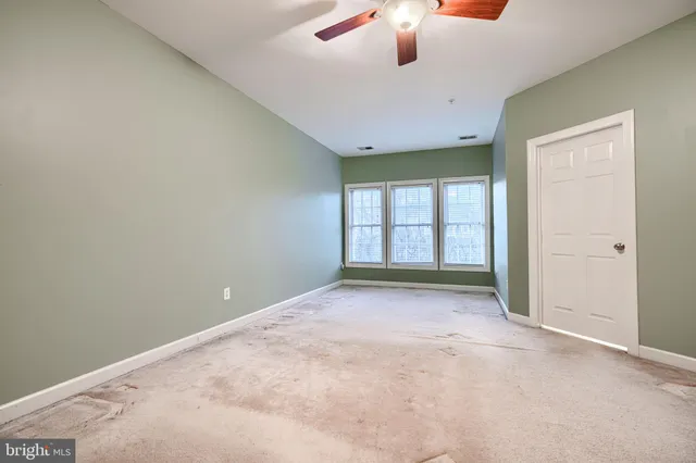 an empty room with windows and ceiling fan