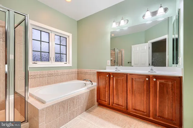 a spacious bathroom with a tub sink shower and mirror