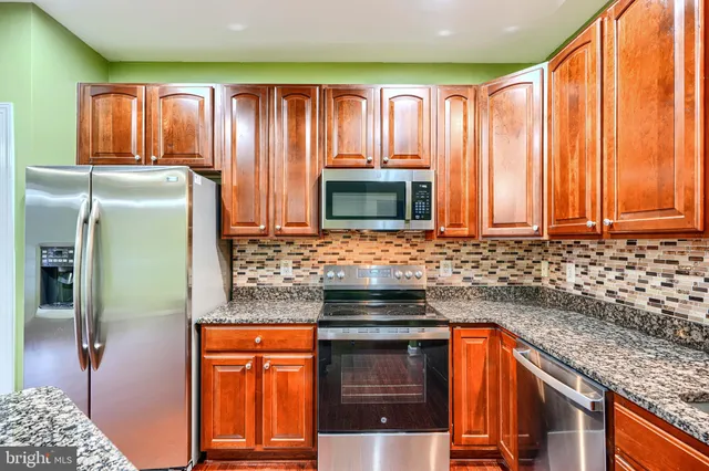 a kitchen with stainless steel appliances granite countertop a refrigerator and a sink