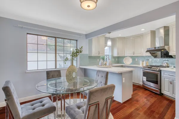 a kitchen with granite countertop a stove a sink a dining table and chairs