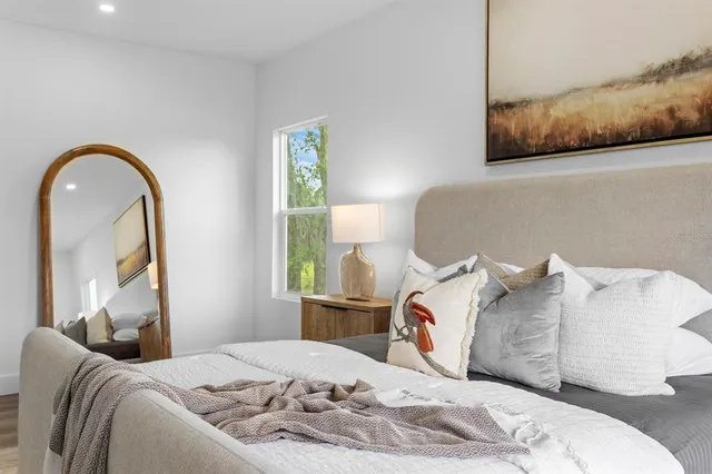 a bed sitting in a bedroom next to a window with wooden floor