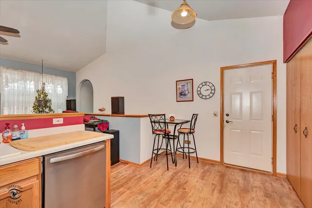 a dining hall with a stove a refrigerator a dining table and chairs with wooden floor