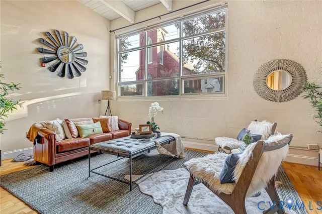 a living room with furniture a chandelier and a dining table with wooden floor