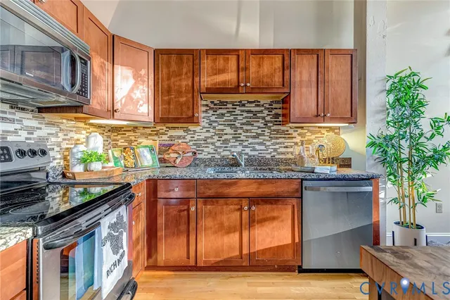 a kitchen with stainless steel appliances granite countertop a stove a sink and a microwave