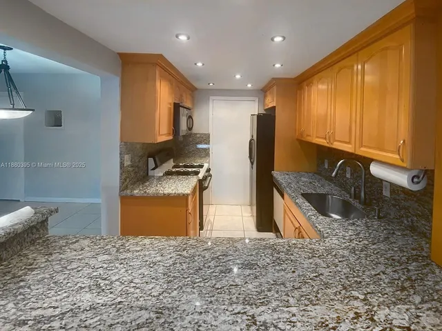 a kitchen with stainless steel appliances granite countertop a sink stove and refrigerator