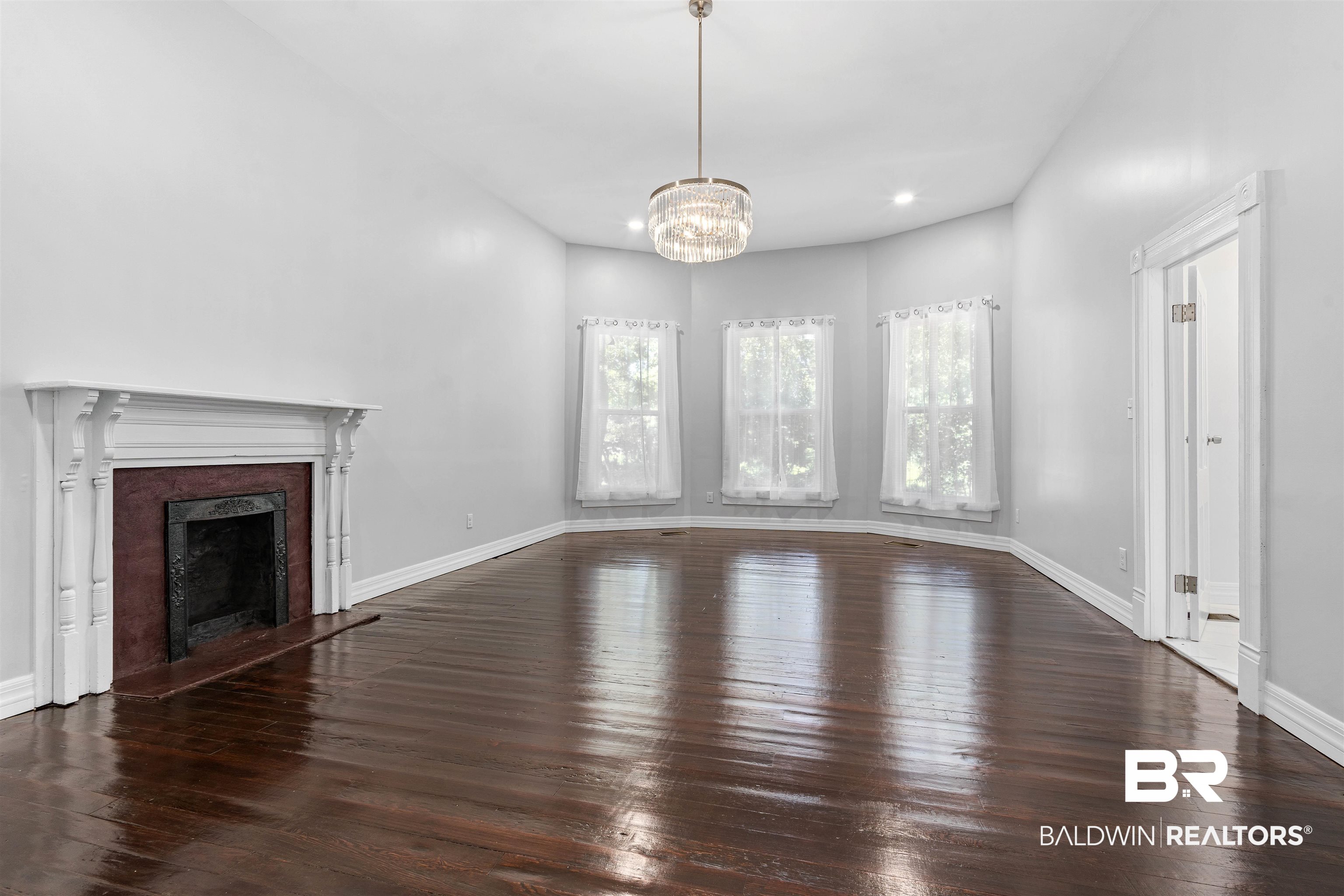 407 East 2nd Street Bay Minette, AL 36507 - Photo 7 of 40 Unfurnished living room with dark wood-style flooring, a fireplace with raised hearth, a chandelier, and recessed lighting