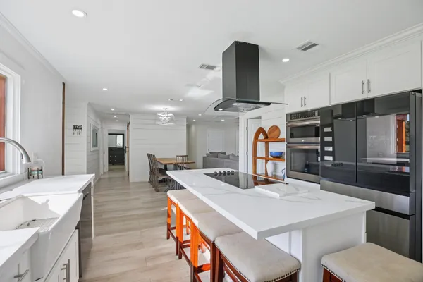 a kitchen with stainless steel appliances kitchen island granite countertop a table chairs in it and wooden floors