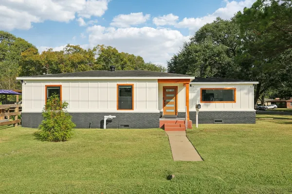 a front view of house with yard and trees in the background