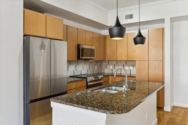 a kitchen with stainless steel appliances granite countertop a sink a refrigerator and a wooden floor