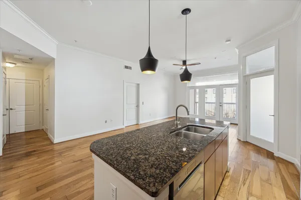 a kitchen with stainless steel appliances granite countertop a sink a refrigerator and wooden floor