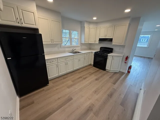 a kitchen with granite countertop a refrigerator a sink dishwasher and wooden cabinets with wooden floor