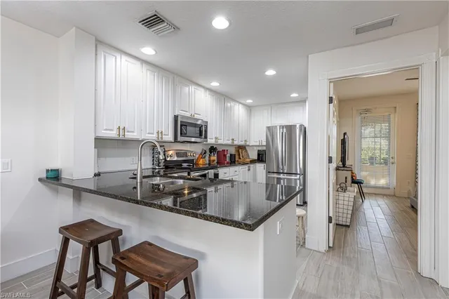 a kitchen with granite countertop white cabinets and stainless steel appliances