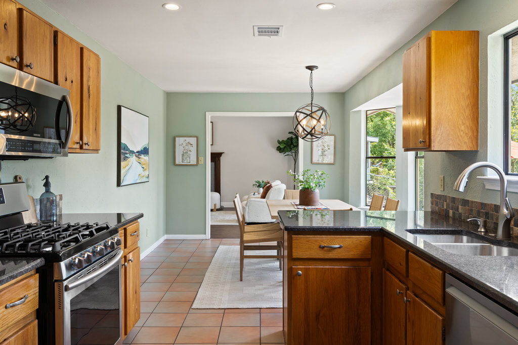 7812 Turquoise Trail Austin, TX 78749 - Photo 16 of 28 a kitchen with stainless steel appliances granite countertop a stove top oven a sink dishwasher a dining table and chairs with wooden floor