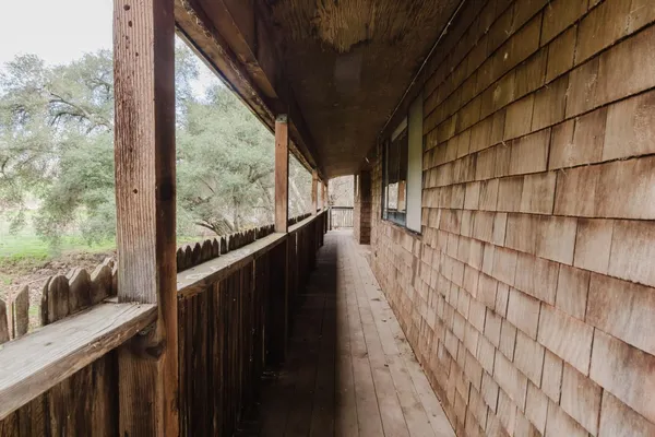 a view of a balcony with wooden floor next to a yard