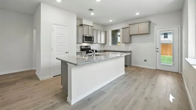 a kitchen with a sink cabinets and wooden floor