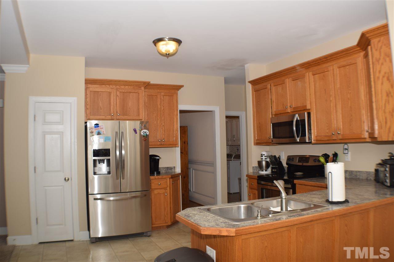 395 Steve Ridge Willow Spring, NC 27592 - Photo 10 of 21 a kitchen with stainless steel appliances granite countertop a refrigerator a stove and a sink with wooden floor