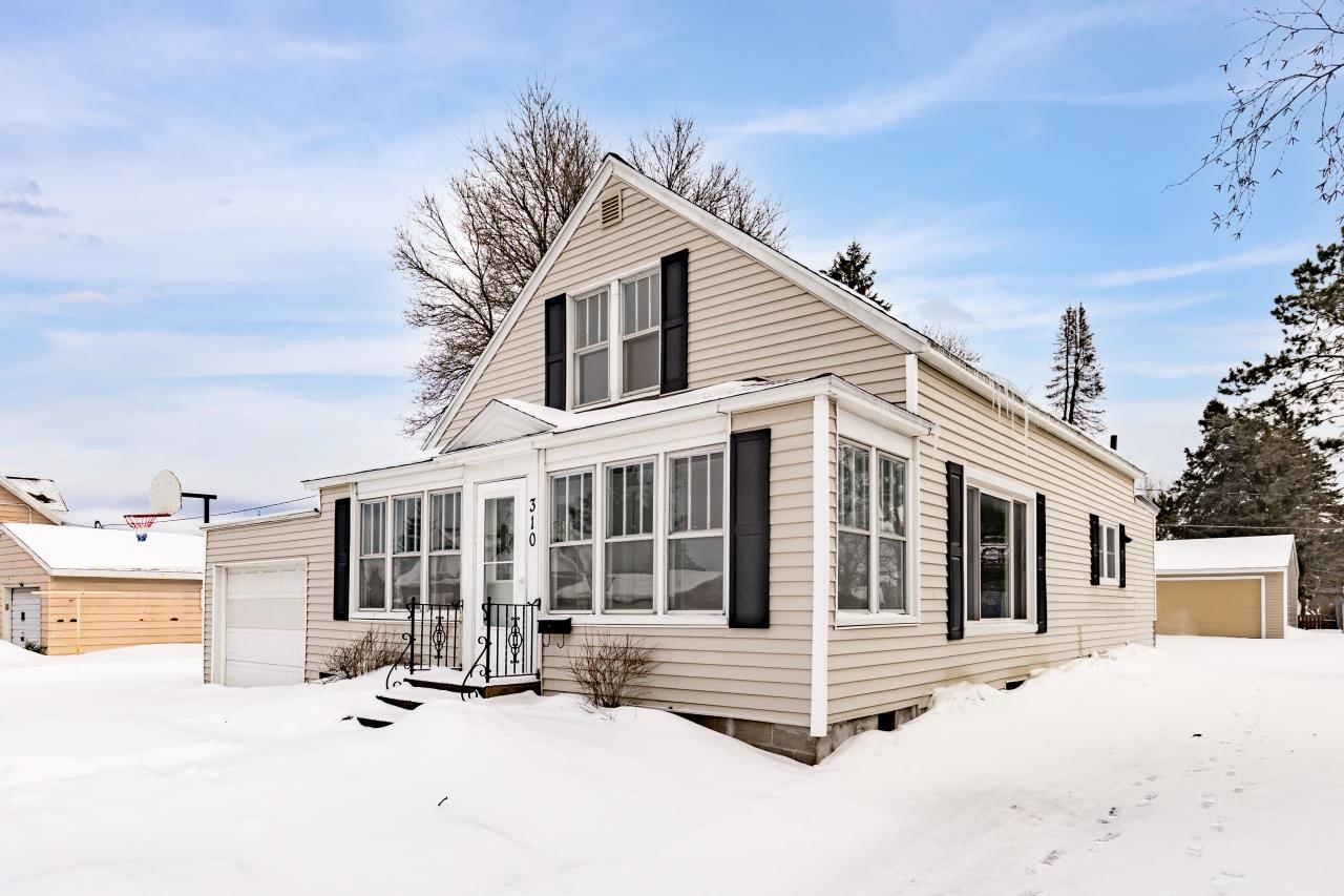 Snow covered house with an outbuilding and a sunroom